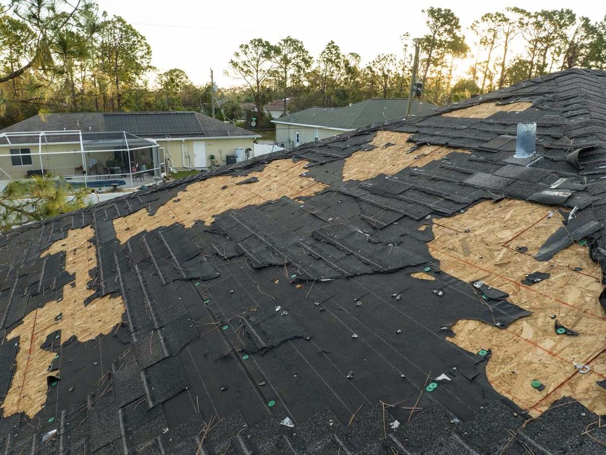 Wind-damaged roof with missing asphalt shingles awaiting inspection