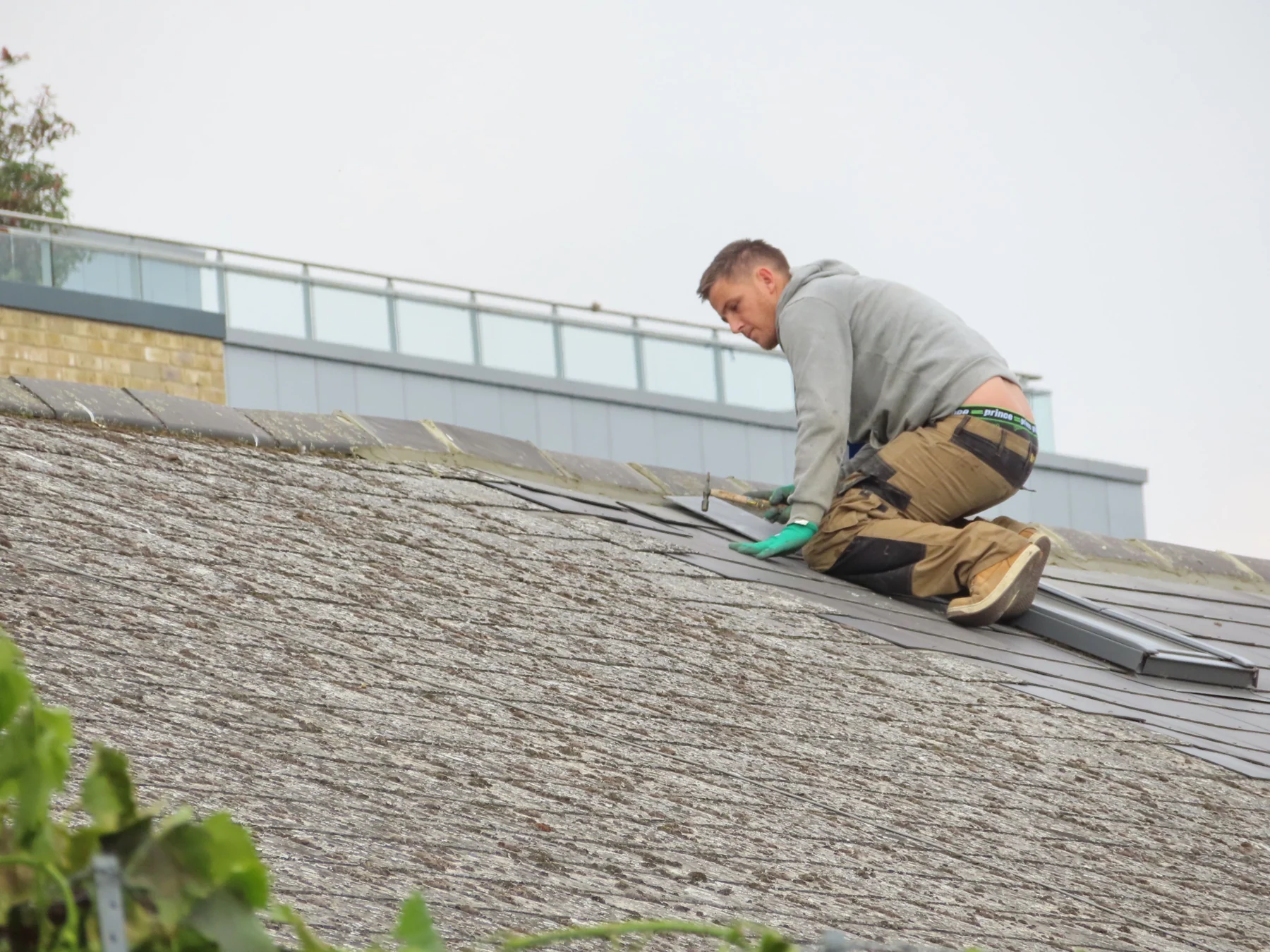 A roofer installing roof covering, photographed from the roof surface
